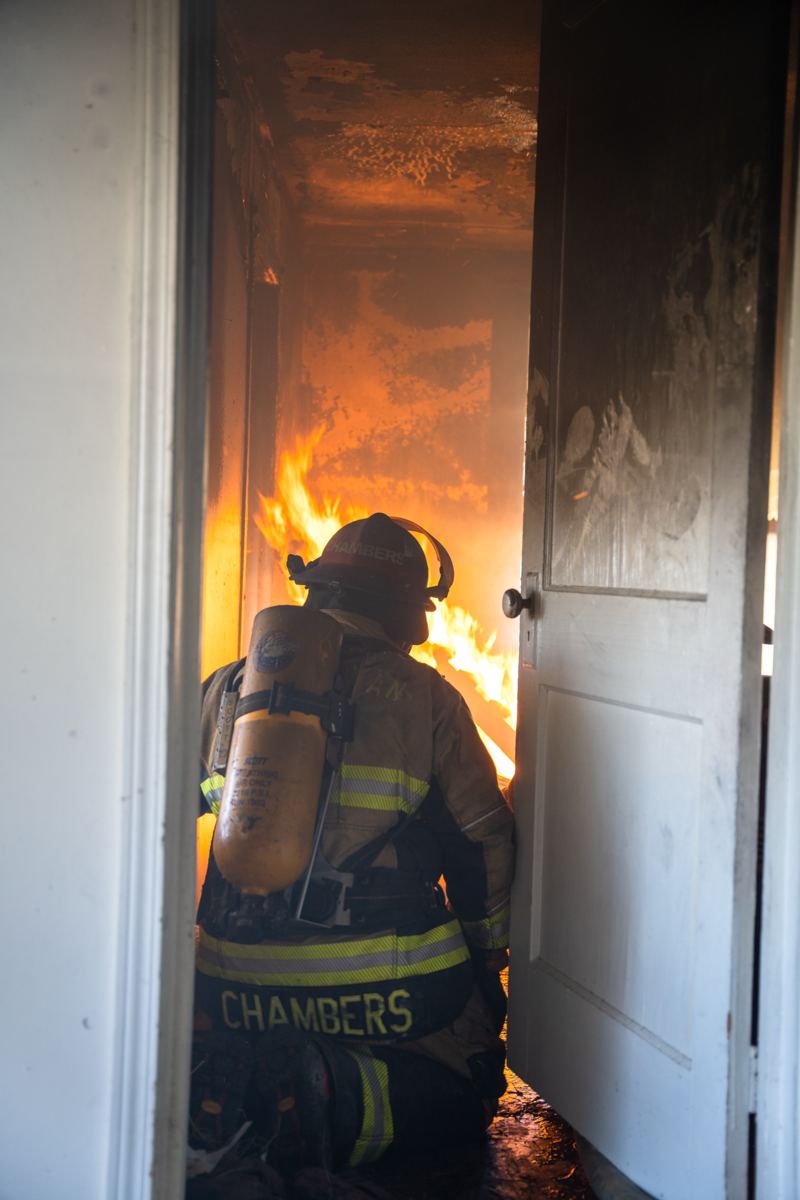 Ben Chambers in firefighting gear entering a burning room during training