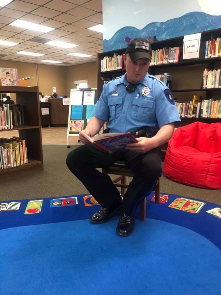 Ben Chambers as a police officer, reading to children at a library