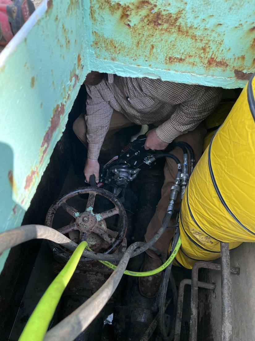 Cutting 8″ ductile iron pipe in a tight vault with a hydraulic saw. Hydraulic equipment helps keep the air quality manageable.