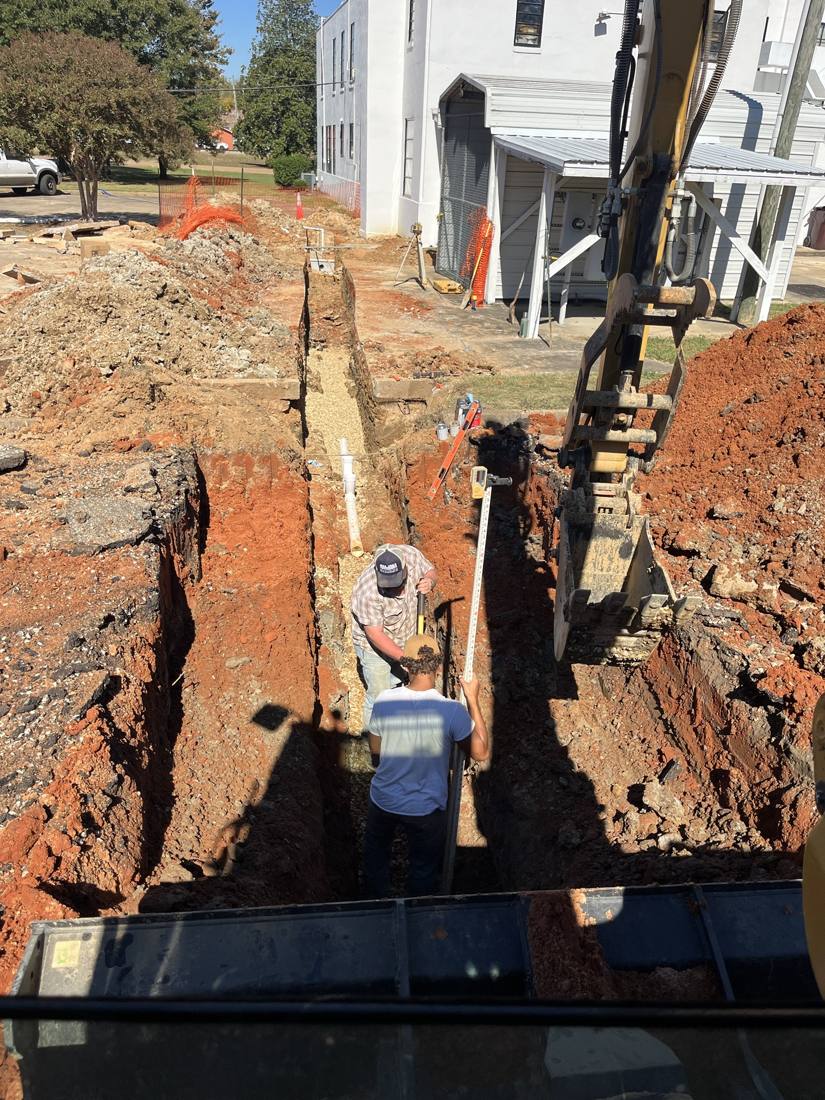 Laying sewer line in a deep trench, checking grade with a laser